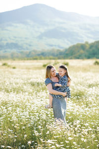 Mother carrying daughter while walking in field