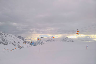 Overhead cable car against snowcapped mountains against sky