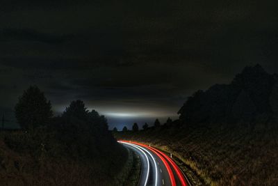 Light trails on road against sky at night