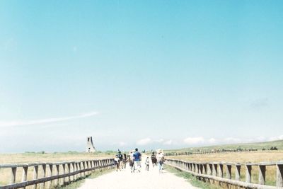 People walking on bridge against clear sky