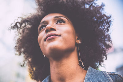 Low angle view of thoughtful young woman with afro hairstyle in city