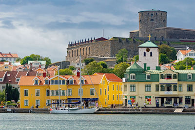 Buildings by river in town against sky