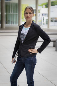 Woman looking away while standing on tile floor against building