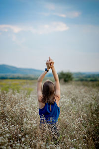 Woman with arms raised on field against sky