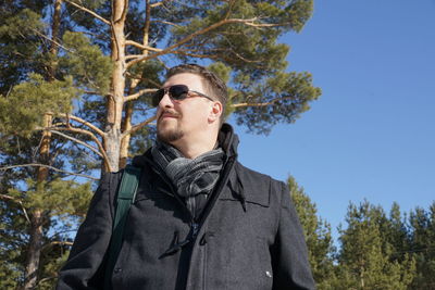 Low angle view of man in warm clothing standing against trees