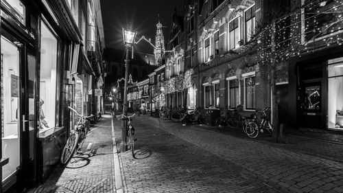 Illuminated street amidst buildings in city at night