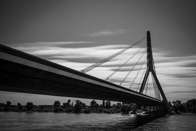 Low angle view of bridge over river against cloudy sky