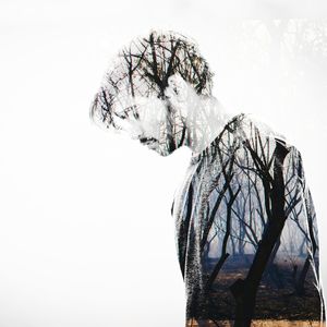 Double exposure of young man and bare trees