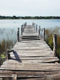 Wooden jetty on pier over lake against sky