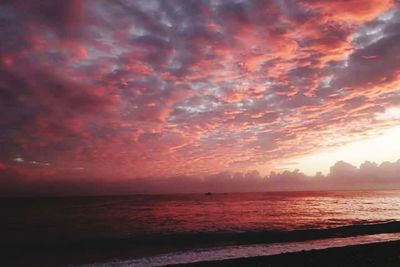 Scenic view of sea against cloudy sky at sunset