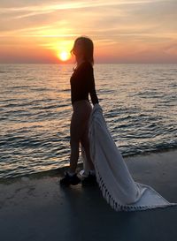 Woman on beach against sky during sunset