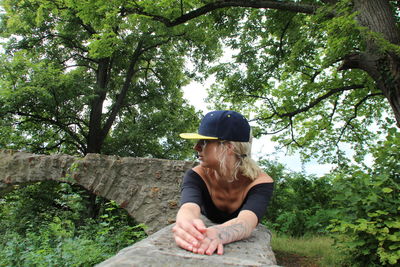 Full length of woman sitting against trees