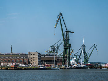 Sailboats in harbor against clear sky