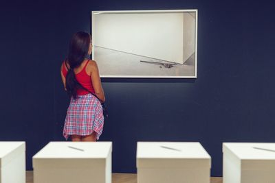 Rear view of woman standing against wall in museum