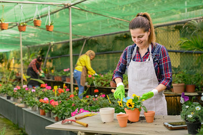 Glad woman planting viola flower into pot