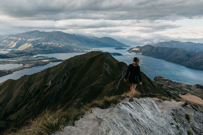 Rear view of woman standing on mountain against sky