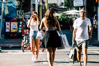 Rear view of women walking on footpath in city