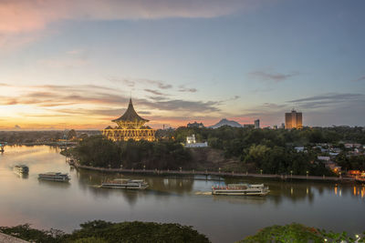 River in city against sky during sunset