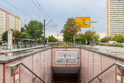 Information sign on railroad tracks by buildings in city against sky