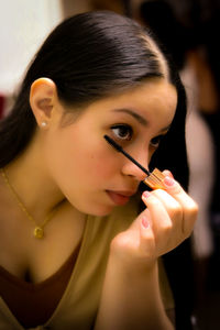 Close-up of young woman applying make-up at home