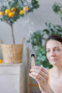 Close-up of young woman blowing flowers