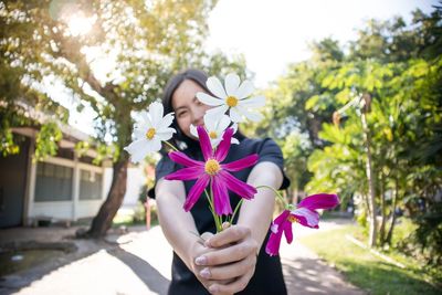 Low angle view of woman holding purple flowering plant