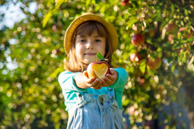 Girl wearing hat holding fresh apple