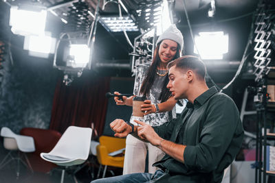 Young man is preparing for tv online broadcast. woman helps with make up.