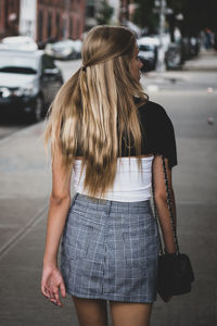 Rear view of teenage girl walking on footpath in city