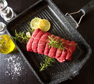 High angle view of fish with lemon slices and herbs in cooking pan