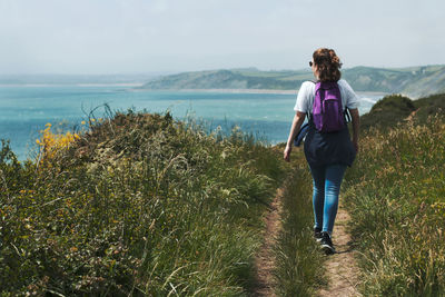 Full length of young woman standing by sea against sky