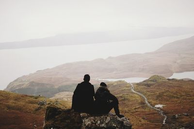 Couple sitting on top of rock