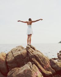 Rear view of woman standing at beach against clear sky