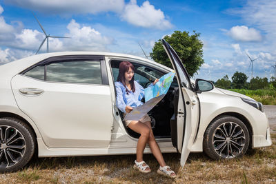 Woman holding map sitting in car