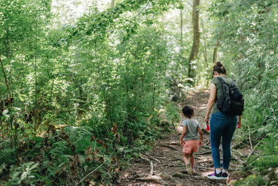 Full length of mother and daughter walking in forest