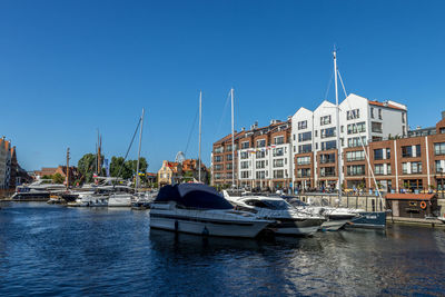 Sailboats moored at harbor against buildings