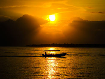 Silhouette boat in sea against sky during sunset