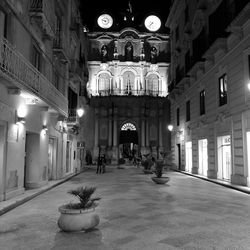 Illuminated street amidst buildings in city at night