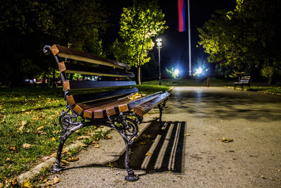 Empty bench in park at night