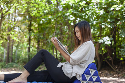 An asian businesswoman spends her free time working on a tablet pc while lying on a sofa.