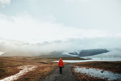 Rear view of man standing on mountain against sky