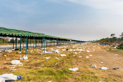 Garbage on grassy landscape against sky during sunny day