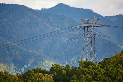 Low angle view of electricity pylon against mountain
