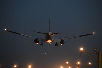 Low angle view of airplane flying against sky at night