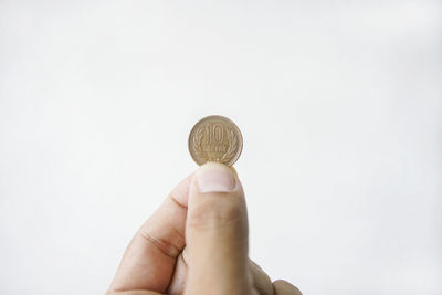 Close-up of hand holding coin against white background