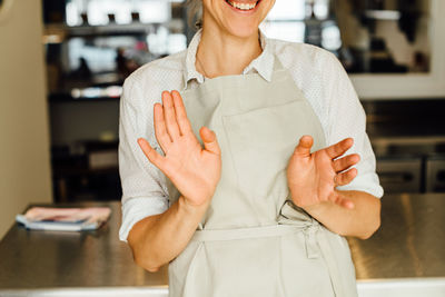 Midsection of female chef in apron and making gestures and smiling