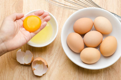 Close-up of hand holding egg yolk at table