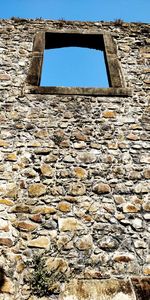 Low angle view of weathered wall against sky
