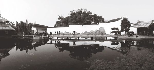 Reflection of trees in swimming pool against clear sky