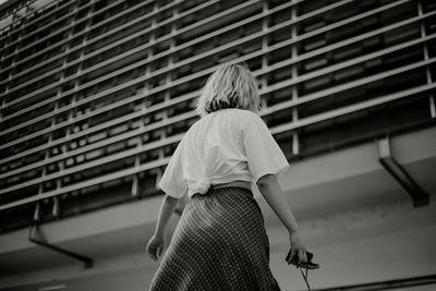 Rear view of woman standing against the wall